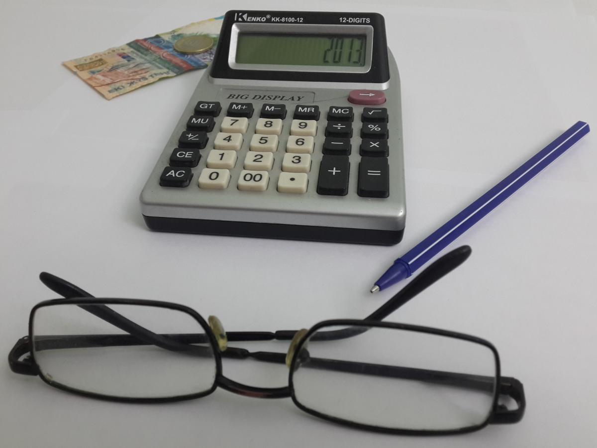 калькулятор, ручка, очки и купюра 